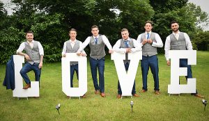 Groom and his best men with LOVE letters at wedding at Pinewood Hotel, Slough